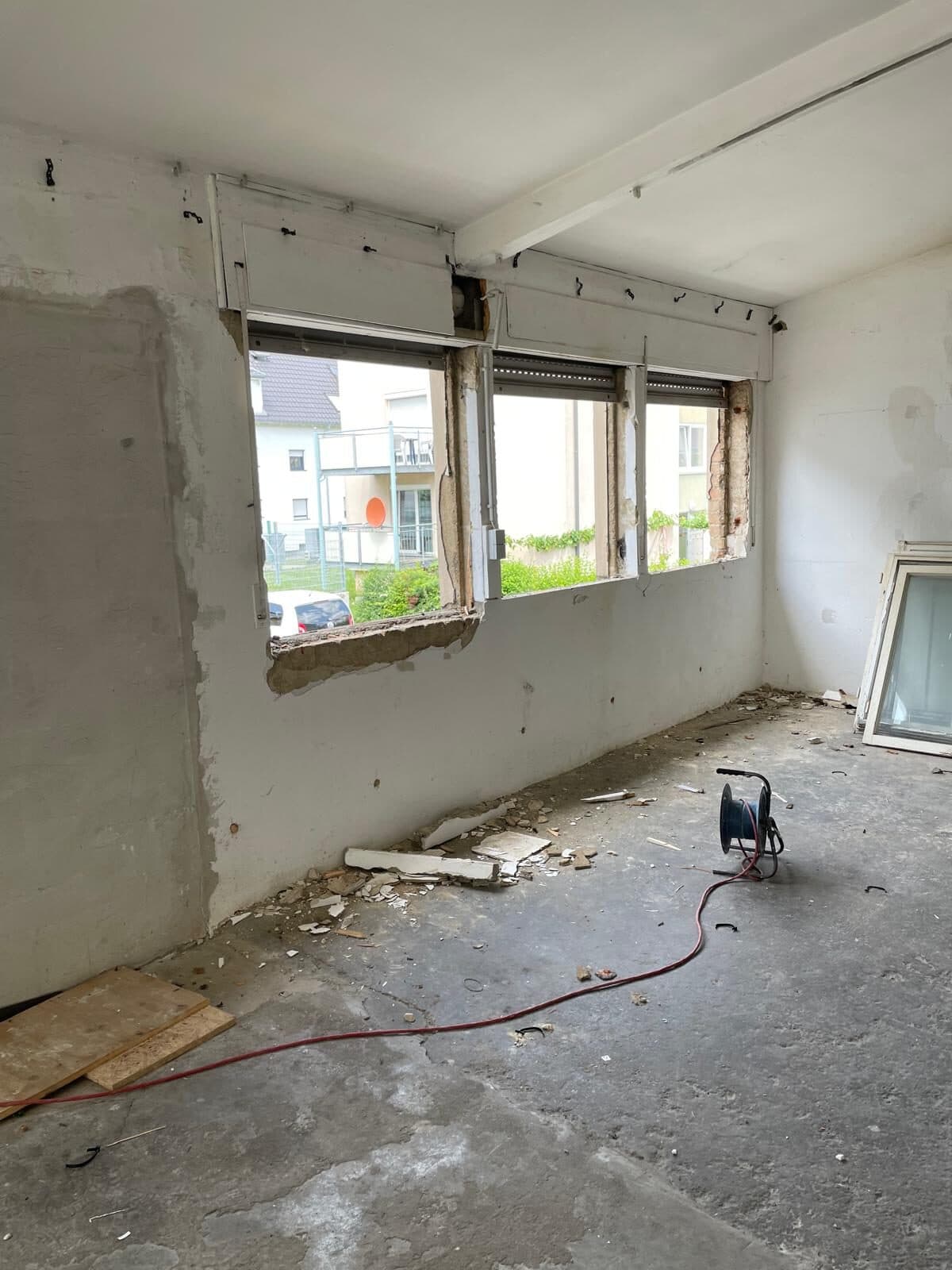 Innenraum des alten Gebäudes: herausgebrochene Fenster, Schutt am Boden, eine Kabeltrommel