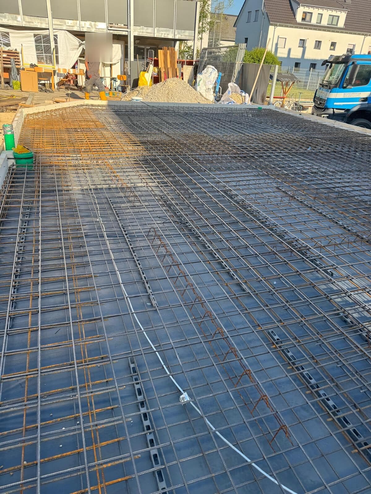 Verlegte Stahlbewehrung für das Fundament des Jugendraums, im Hintergrund eine Betonpumpe