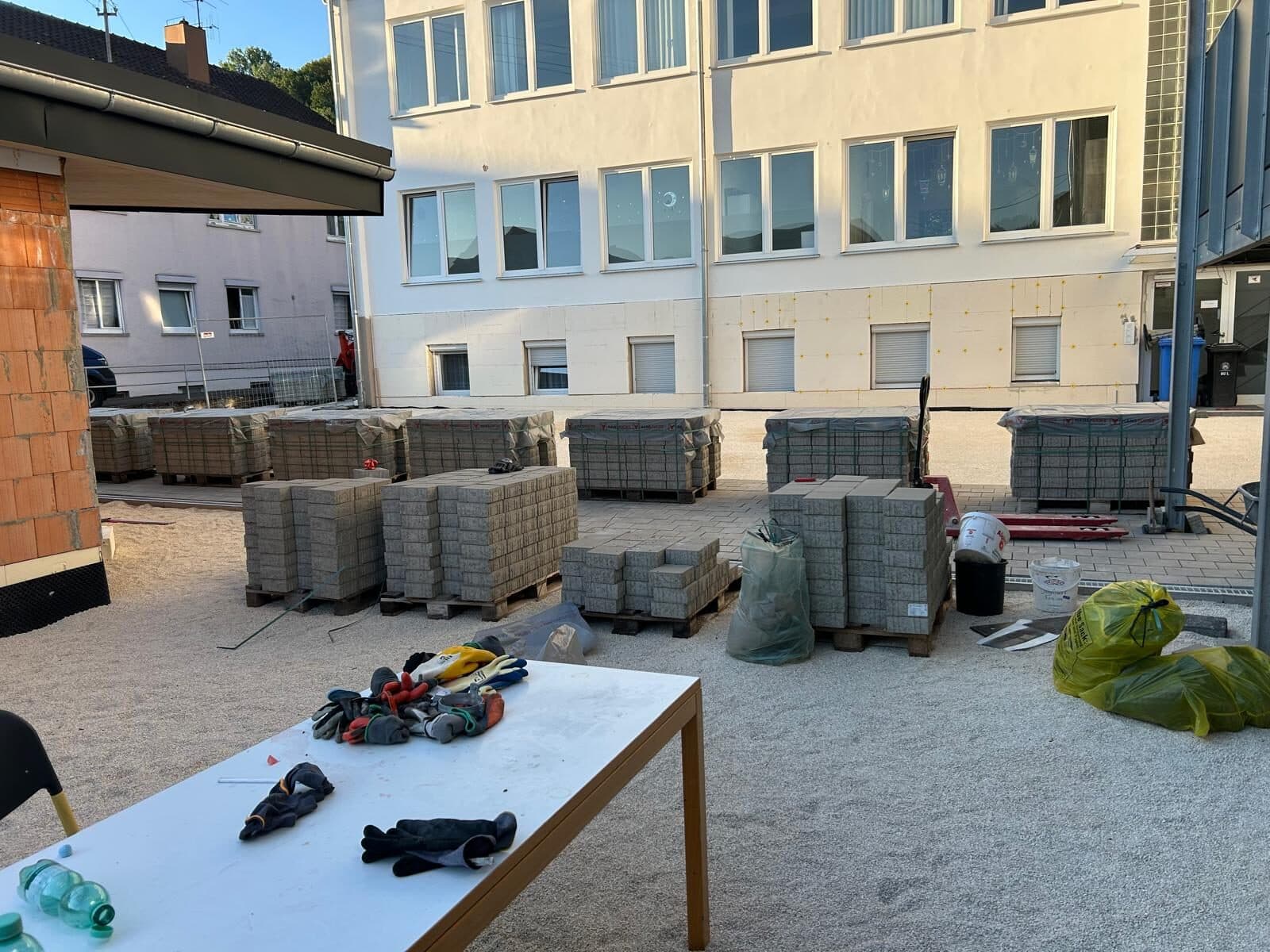 Paletten mit Pflastersteinen auf dem Hof vor dem Neubau